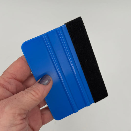 Blue 4-inch felt-edge decal squeegee held in hand for scale